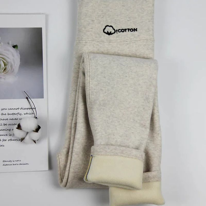 Legging polaire beige thermique pour femme Legging beige, plier avec le bas retroussé pour voir la doublure. Une écriture noire est brodée au niveau de la taille.