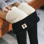 Mannequin assise sur un canapé orange, on ne voit que ses jambes et pas ses pieds. Elle porte un legging noir retroussé de la taille jusqu'aux genoux pour voir la doublure blanche en velours.