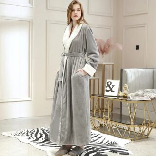 Mannequin femme blonde, debout sur un tapis zèbre, elle porte un peignoir long gris doublé en peluche blanche, et des chaussons gris. Elle a les mains dans les poches.