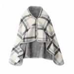 Poncho couverture, avec trois boutons, beige avec lignes noires et grises qui forment des carreaux. Doublé en velours gris. Sur fond blanc.