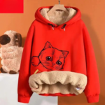 Sweat polaire femme avec capuche et imprimé de chat sur un cintre sur fond orange
