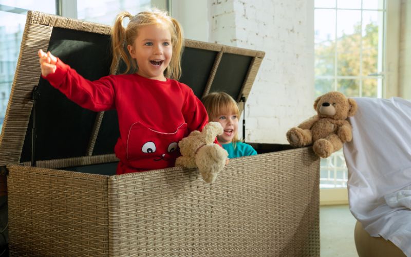 Les Polaires pour Enfants et Ados : Comment Trouver l'Équilibre entre Mode et Praticité Deux enfants qui jouent dans un grand coffre ouvert, chacun porte une polaire.